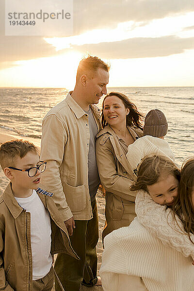Glückliche Familie  die bei Sonnenuntergang gemeinsam Spaß an der Küste hat