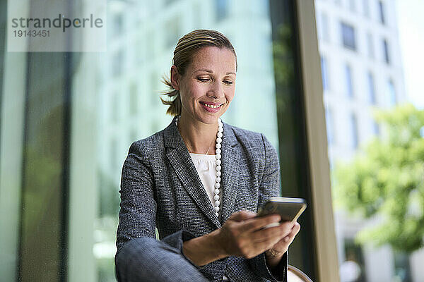 Smiling businesswoman text messaging through smart phone