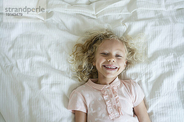Lächelndes Mädchen entspannt sich zu Hause im Bett