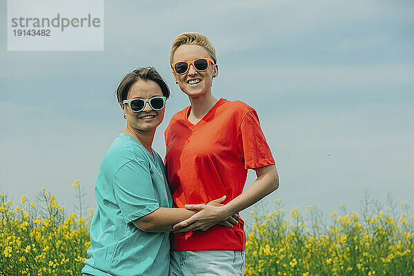 Fröhliche Lesben mit Sonnenbrille stehen auf dem Feld