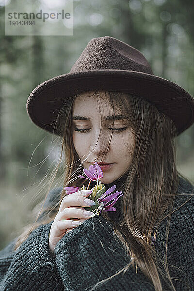 Schöne junge Frau mit langen Haaren  die nach Blumen riechen