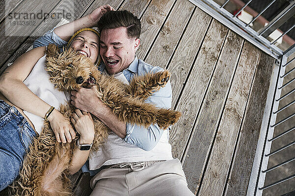 Glückliches junges Paar genießt es mit Hund auf dem Balkon