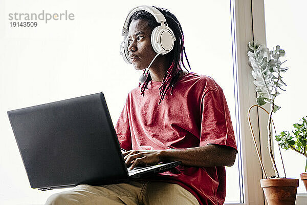 Nachdenklicher Mann mit Headset und Laptop zu Hause