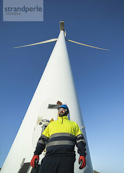 Reifer technischer Ingenieur vor einer hohen Windkraftanlage