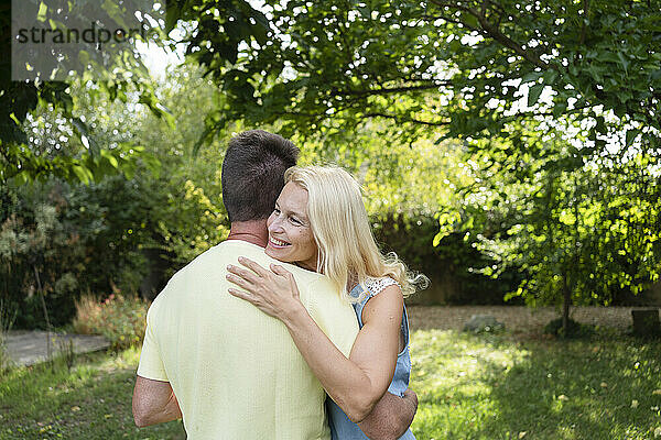 Glückliche reife Frau umarmt Mann im Hinterhof