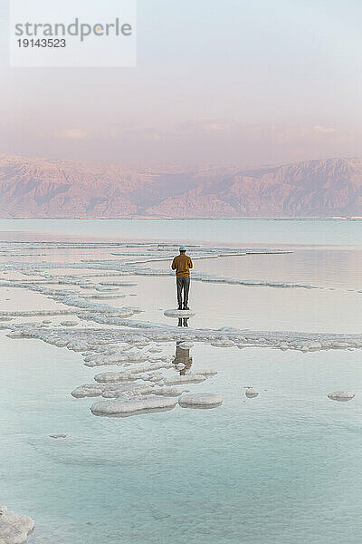 Mann steht auf Salzformationen im Toten Meer