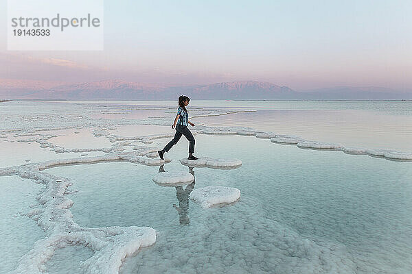 Junge Frau geht auf Salzformationen im Toten Meer