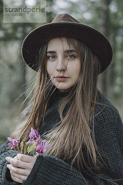 Schöne junge Frau mit langen Haaren  die Blumen hält