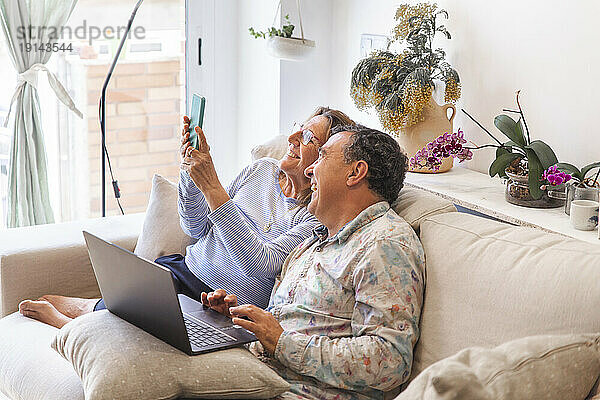 Glückliches Seniorenpaar verbringt seine Freizeit mit drahtlosen Technologien zu Hause