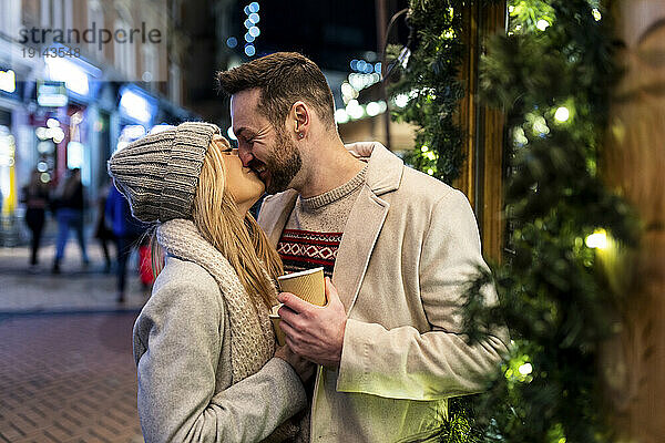Glückliches Paar küsst und umarmt sich auf dem Weihnachtsmarkt
