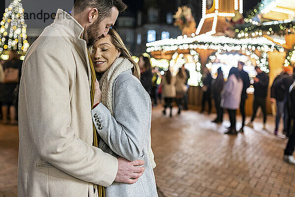 Glückliches Paar umarmt sich auf dem Weihnachtsmarkt