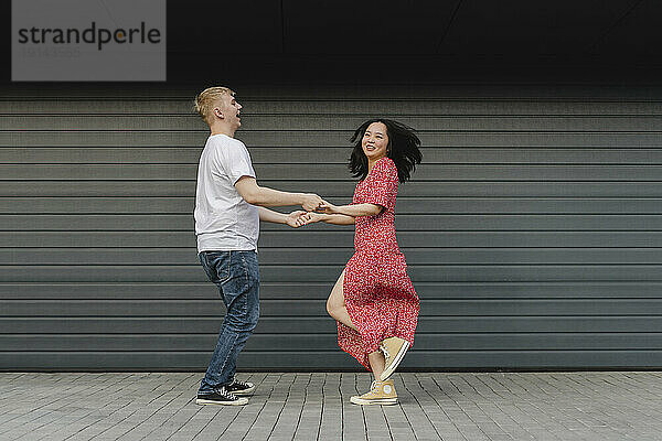 Romantic young couple dancing in front of closed shutter