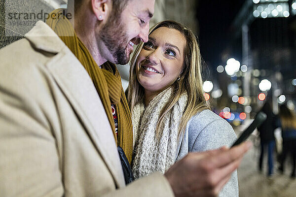 Glückliche junge Frau mit Mann  der Smartphone hält