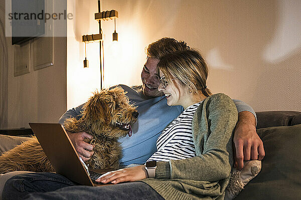 Happy man and woman having fun with dog at home