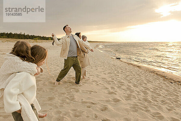 Vater wirft Stock mit Familie und verbringt Zeit am Strand