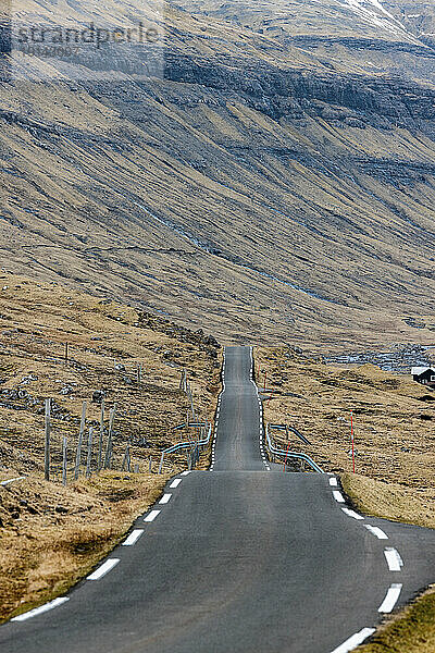 Leere Straße  die in Richtung Berge führt  Färöer-Inseln