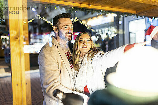Glücklicher Mann und Frau beim Einkaufen auf dem Weihnachtsmarkt
