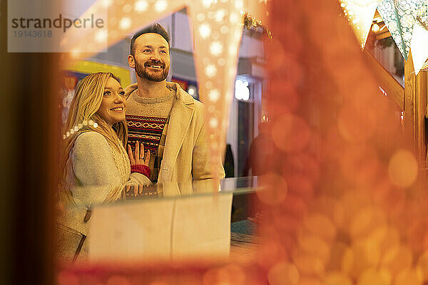 Lächelnde junge Frau mit Mann beim Einkaufen auf dem Weihnachtsmarkt