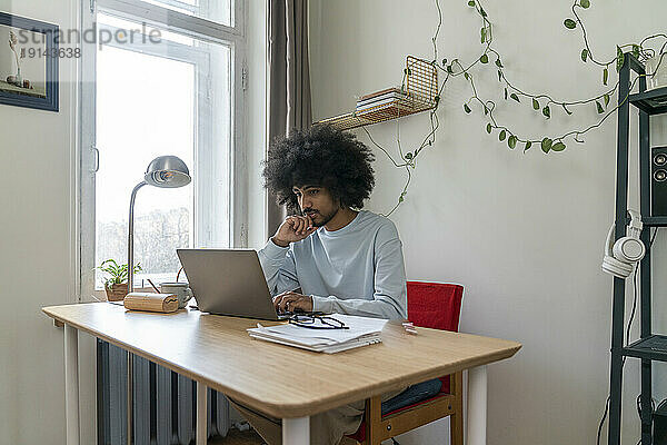 Freiberufler mit der Hand am Kinn  der im Heimbüro arbeitet