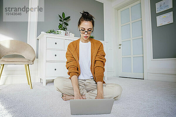 Freiberufler mit Brille arbeitet zu Hause am Laptop