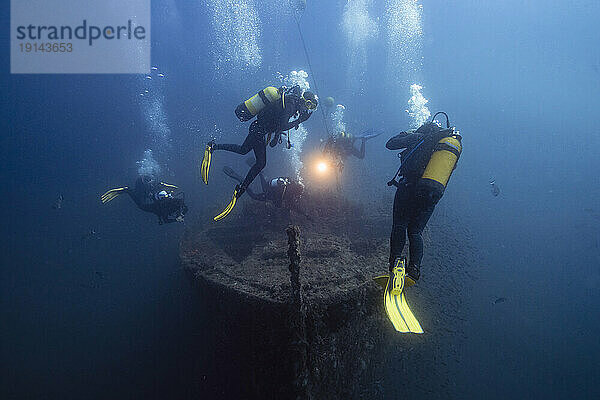 Männer und Frauen untersuchen das versunkene Schiff El Naranjito unter Wasser