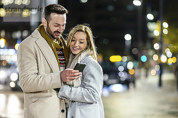 Glücklicher Mann und Frau  die unterwegs ihr Mobiltelefon benutzen