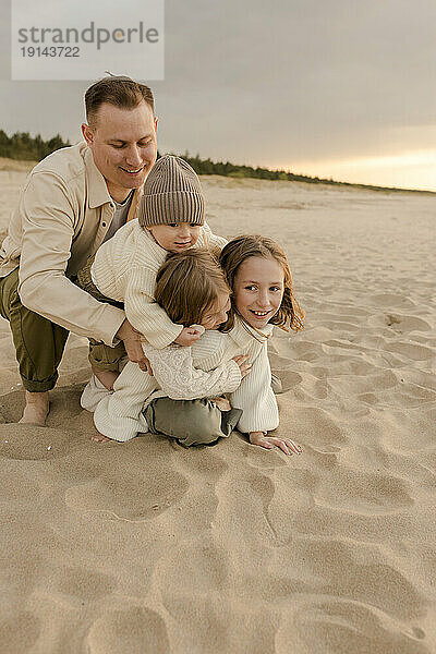 Glücklicher Mann  der mit Sohn und Töchtern am Strand genießt