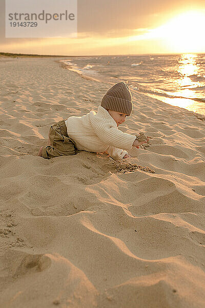 Cute baby boy playing in sand at beach