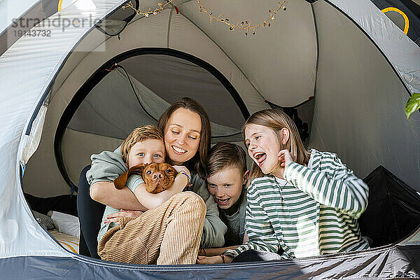 Glückliche Familie mit Vizsla-Hund  die zu Hause im Zelt genießt