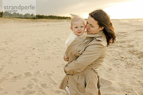 Lächelnde Mutter umarmt Sohn am Strand