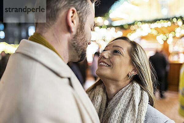 Lächelnde Männer und Frauen genießen den Weihnachtsmarkt