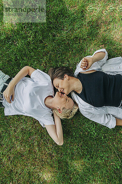 Lesbian couple kissing lying on grass