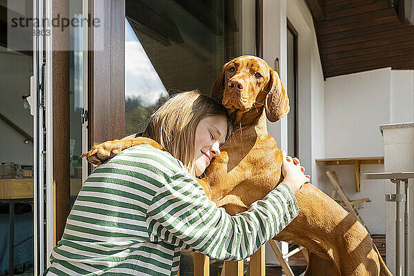 Lächelndes Mädchen umarmt Vizsla-Hund zu Hause