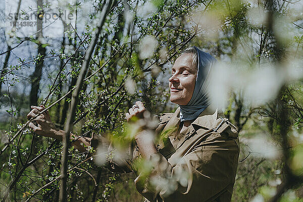 Reife Frau riecht Blumen im Wald