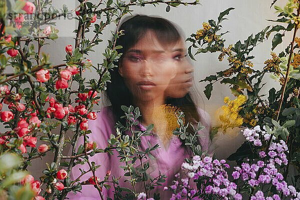 Multiple image of young woman amidst colorful flowers