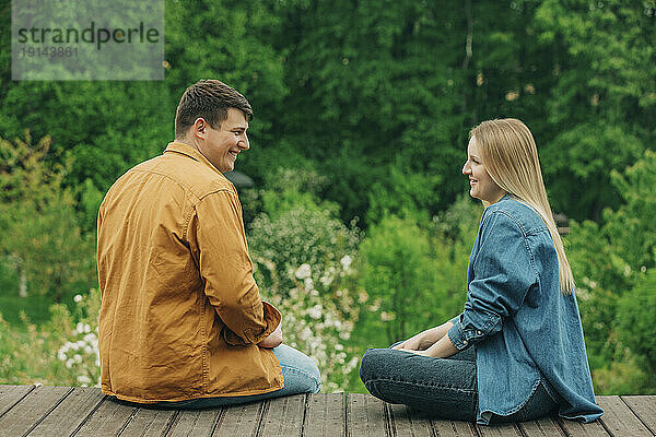 Glückliches Paar sitzt zusammen auf Holzsteg
