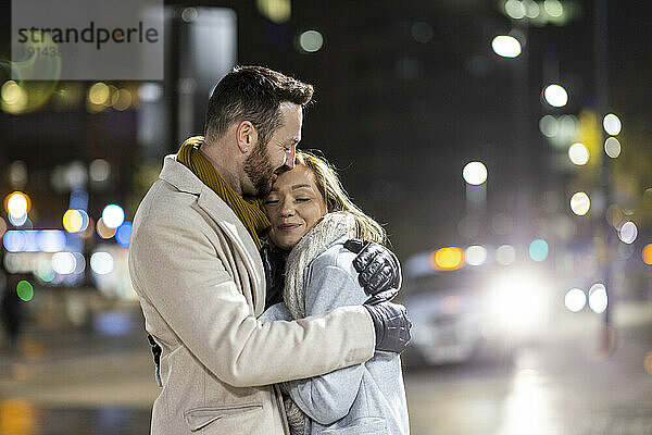 Lächelnde Frau umarmt Mann auf der Straße