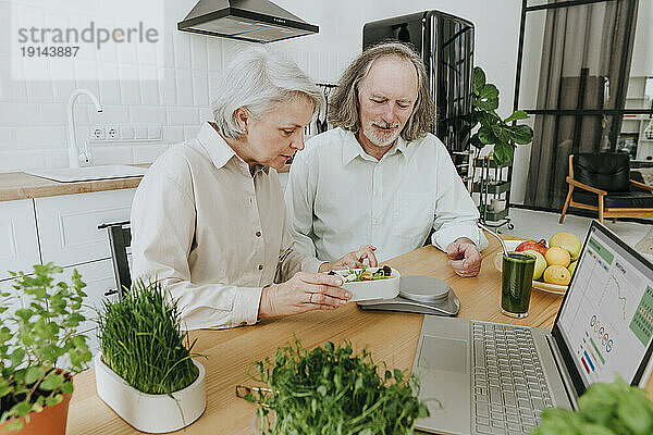 Frau und Mann wiegen Brotdose auf Waage in der heimischen Küche