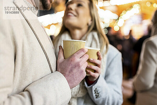 Glückliches Paar mit Kaffeetasse auf dem Weihnachtsmarkt