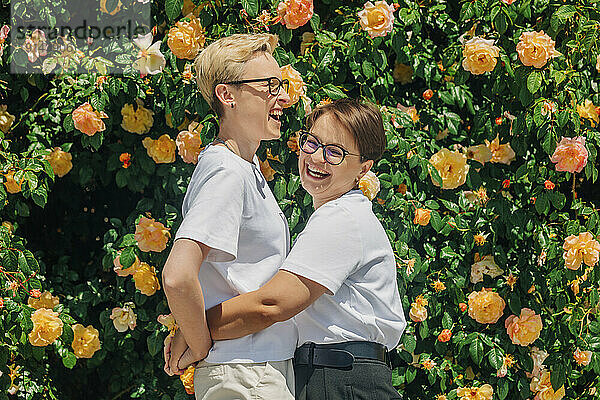 Glückliches lesbisches Paar vor der Wand mit Rosen