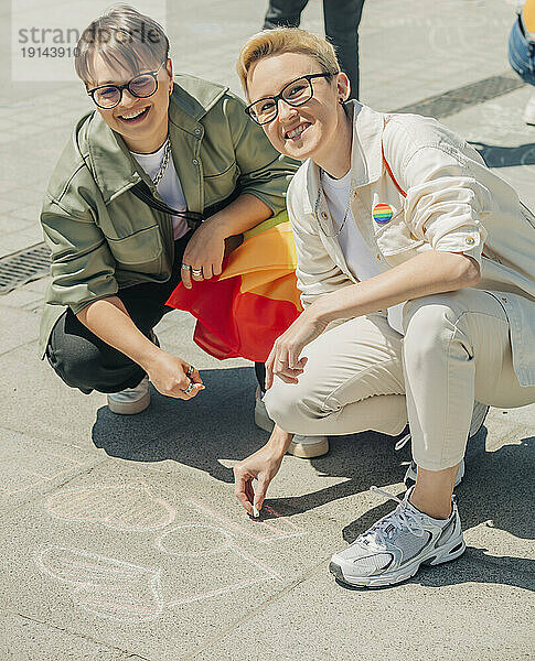 Glückliches lesbisches Paar  das mit Kreide auf den Boden schreibt