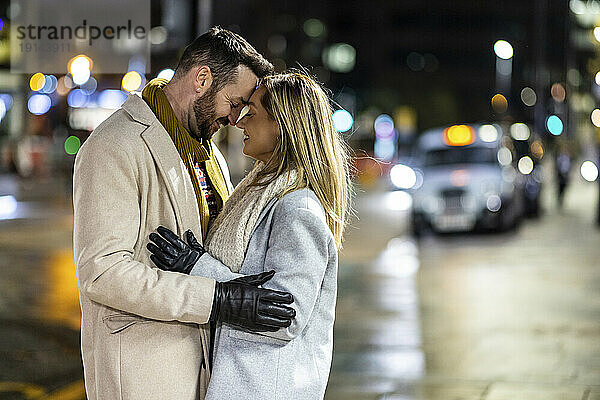 Glücklicher Mann und Frau umarmen sich auf der Straße