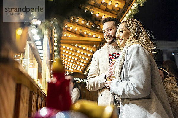 Glückliche junge Frau und Mann beim Einkaufen auf dem Weihnachtsmarkt