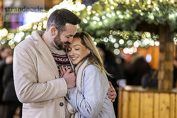 Happy loving couple hugging each other at Christmas market