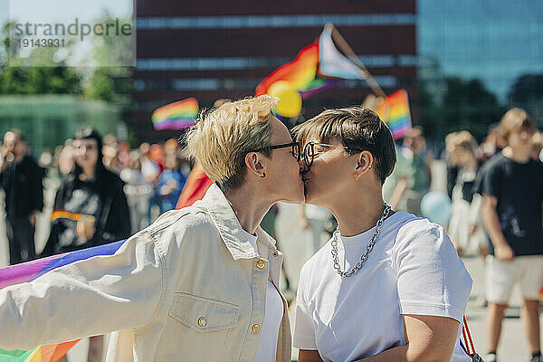 Lesbisches Paar küsst sich an einem sonnigen Tag bei einer Gay-Pride-Veranstaltung