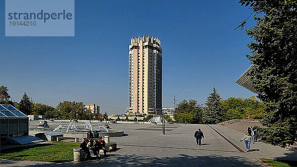 Zentralasien  Kasachstan  Almaty-Stadt. Der Abaï-Platz verfügt über einen öffentlichen Garten mit einer Reihe von mit Granit verkleideten Brunnen. Der so hohe Wolkenkratzer ist auf diesem Platz beeindruckend.