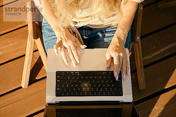 Draufsicht auf weibliche Hände über der Tastatur eines Laptops