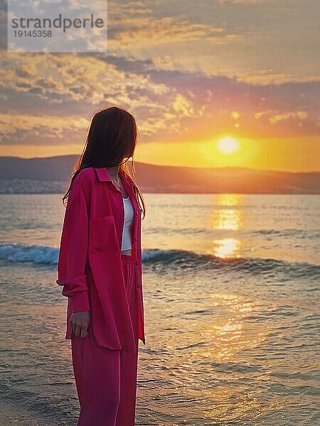 Ästhetische junge Frau Porträt trägt rosa Anzug auf dem Meer Ufer als trifft die Morgendämmerung. Schöne Sonnenaufgang am Strand. Sommerurlaub Hintergrund  Urlaub Entspannung Konzept