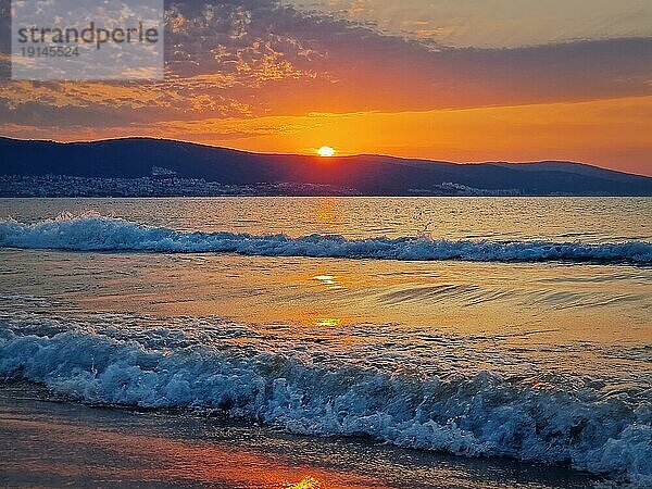 Schöner Sonnenaufgang an der bulgarischen Küste des Schwarzen Meeres. Sunny Beach Resort  Dämmerung Szene mit der Sonne steigt die Hügel am Horizont und schäumenden Wellen waschen den Sand Ufer. Sommerurlaub Ansicht