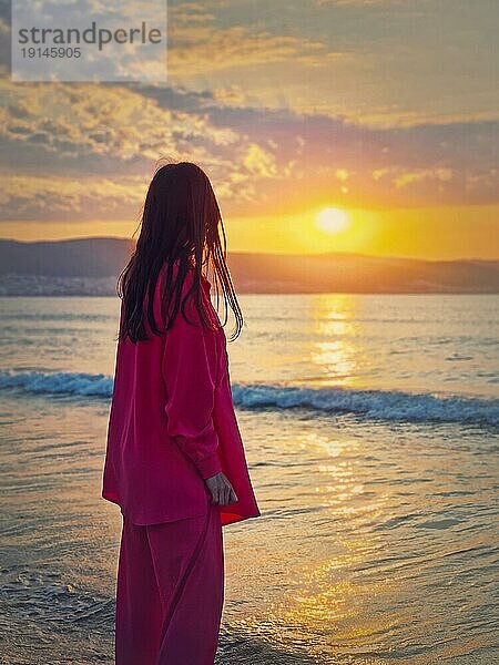 Ästhetische junge Frau Rückansicht beobachten den Sonnenaufgang über den Hügeln am Meer. Schöne Morgendämmerung Szene  Sommerurlaub Hintergrund